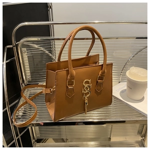 Detail of brown faux leather handbag featuring golden SSS logo and chain tassel accents