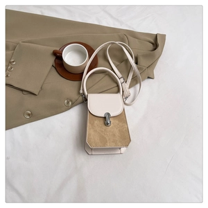 Detail of minimalist cream and khaki crossbody bag with elegant silver metal flip lock