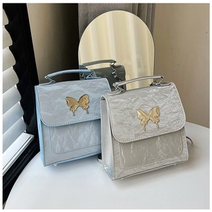 Detail of light blue and silver textured handbags featuring a golden butterfly buckle
