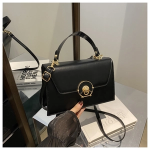 Detail of black matte leather handbag with gold circular metal buckle and sturdy handle