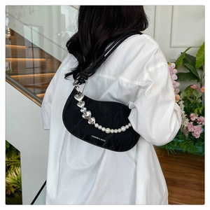 Detail of black hobo bag featuring silver heart and pearl decorative chain elements