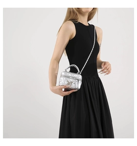 Macro shot of silver quilted mini bag featuring a butterfly clasp and metal chain strap