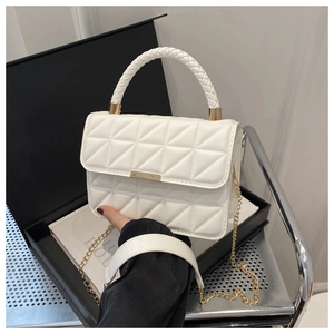 Detail of white quilted handbag with gold metal bar closure and woven top handle