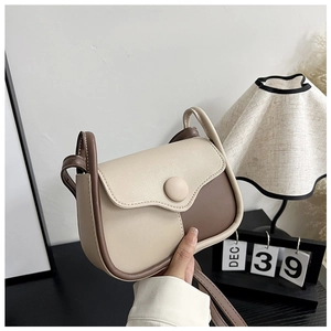 Close-up of contrast color saddle crossbody bag with refined texture and round buckle