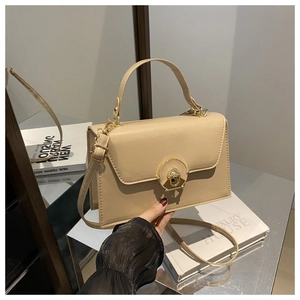 Detail of beige structured crossbody bag with gold round metal lock and textured leather