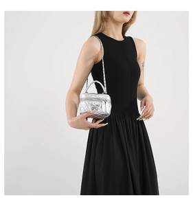 Detail of silver quilted mini bucket bag featuring a butterfly metal clasp on a model