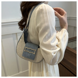Détail du sac croissant tissé avec bordure en denim bleu et boucle dorée sur le mannequin