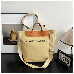 Detail of beige canvas tote bag with brown leather handles and Light Fashion print
