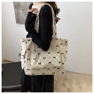 Detail of corduroy tote bag featuring bow patterns and functional side pockets for women