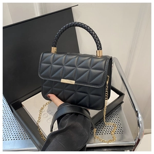 Detail of black quilted leather handbag featuring a gold buckle and metal chain strap