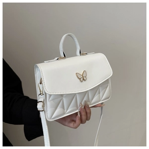 Detail of white quilted crossbody bag featuring a golden butterfly twist lock closure