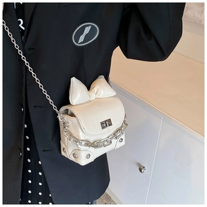 Detail van mini crème witte vierkante tas met krokodillenpatroon en strik bij een model