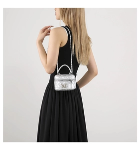 Detail of silver metallic quilted vanity bag with butterfly emblem worn by model