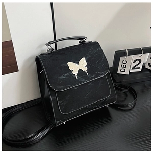 Detail of black pleated texture bag featuring a silver butterfly metal buckle closure
