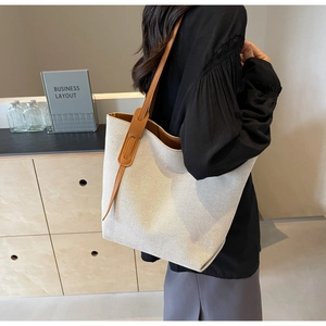 Close-up of large canvas tote bag showing contrast leather straps and woven texture