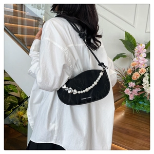 Detail of black crescent shoulder bag with pearl and silver heart charm chain strap