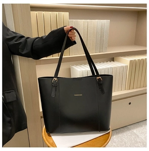 Detail of a black PU leather tote bag featuring golden hardware and logo for daily commute
