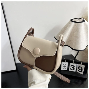 Detail of vintage patchwork shoulder bag featuring contrast colors and a large round buckle