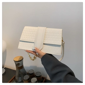 Detailed view of the embossed triangle pattern and gold chain on the white flap handbag