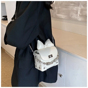Close-up of white mini square bag featuring a large bow and elegant silver chain strap
