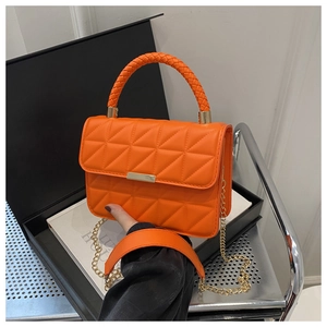 Detail of bright orange quilted bag with woven round handle and gold chain strap