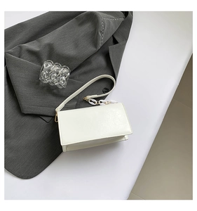White rectangular shoulder bag featuring a thick acrylic chain and textured faux leather
