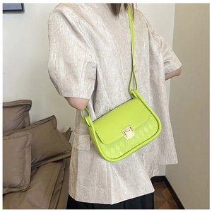 Neon yellow quilted crossbody bag with gold lock shown on model with satin shirt