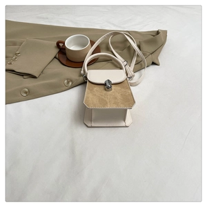 Detail of cream faux leather handbag with khaki suede flap and silver twist lock closure
