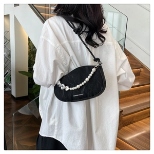 Detail of black crescent shoulder bag with pearl heart chain and pleated texture finish