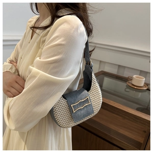 Detail of woven crescent bag with gold geometric buckle and blue denim contrast texture