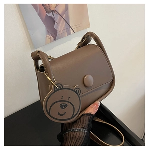 Détail d'un sac besace marron vintage avec boucle ronde et pendentif ourson mignon