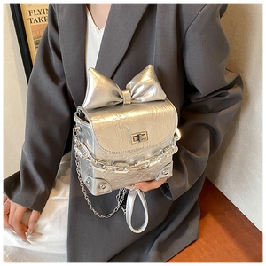 Detail of silver pleated leather mini bag with large bow and metallic chain straps