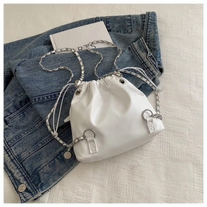 Detail of white leather drawstring bucket bag with silver chain strap on denim jacket