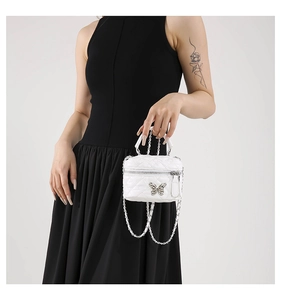 Close-up of a white quilted mini bag with a silver butterfly and metal chain strap