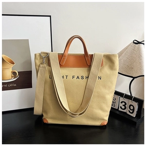 Detail of khaki canvas tote bag with brown leather handles and adjustable shoulder strap