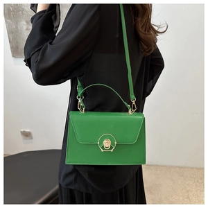 Green leather crossbody bag featuring a distinctive round gold metal lock and shoulder strap