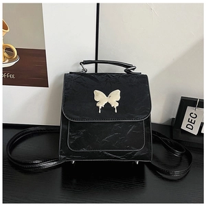 Detail of black pleated PU leather backpack featuring a silver butterfly metallic clasp