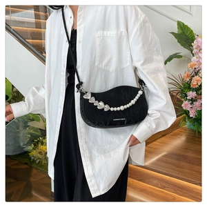Detail of black crescent crossbody bag with pearl heart chain and pleated texture