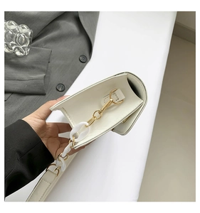 Detail of white PU leather bag featuring gold metal and white acrylic chain straps