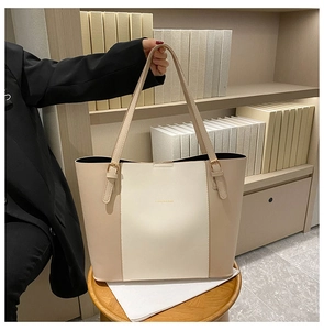 Detail view of the cream and beige PU leather tote bag in a cozy lifestyle setting