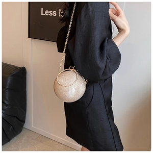 Close-up of a champagne gold sphere evening bag with a round handle and metallic chain