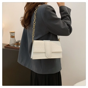 Detail of white woven baguette bag with geometric texture and gold chain strap