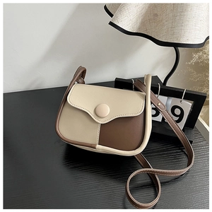 Detail of vintage bicolor small square crossbody bag on a rustic wooden desk
