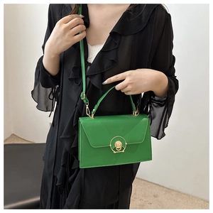 Detail of green glossy leather handbag with gold round twist lock and fine shoulder strap