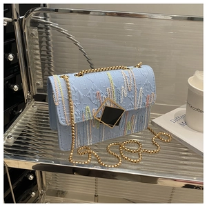 Detail of light blue crossbody bag featuring color stitching and gold metal buckle