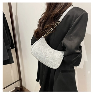 Detail of light gray quilted felt shoulder bag with golden chain on black blazer