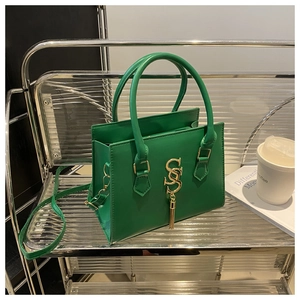 Close-up of emerald green leather handbag with gold S logo and long tassel detail