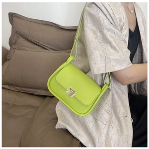 Detail of lime green quilted handbag with a square gold metal lock and leather texture