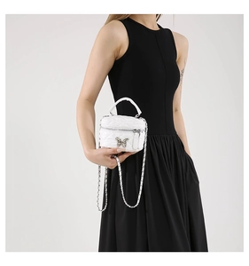 Detail of white quilted vanity bag with silver butterfly clasp and chain strap