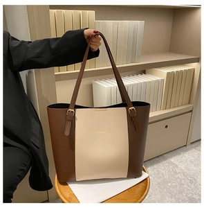 Detail of adjustable PU leather straps with metal buckles on a brown patchwork tote bag